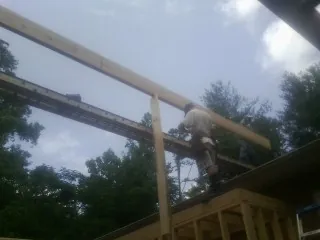 Carpenter setting a ridge beam over a new addition frame — Ice Dam Removal by Roofing Brothers in North Newton