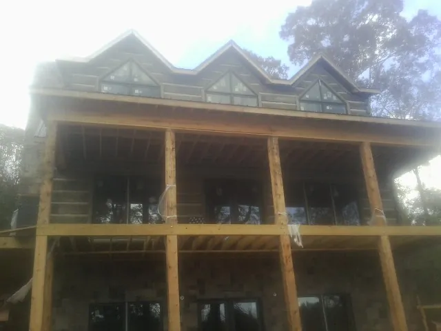Dormers and porch framing on a large log home under construction — Roof Coating work by our crew in North Newton