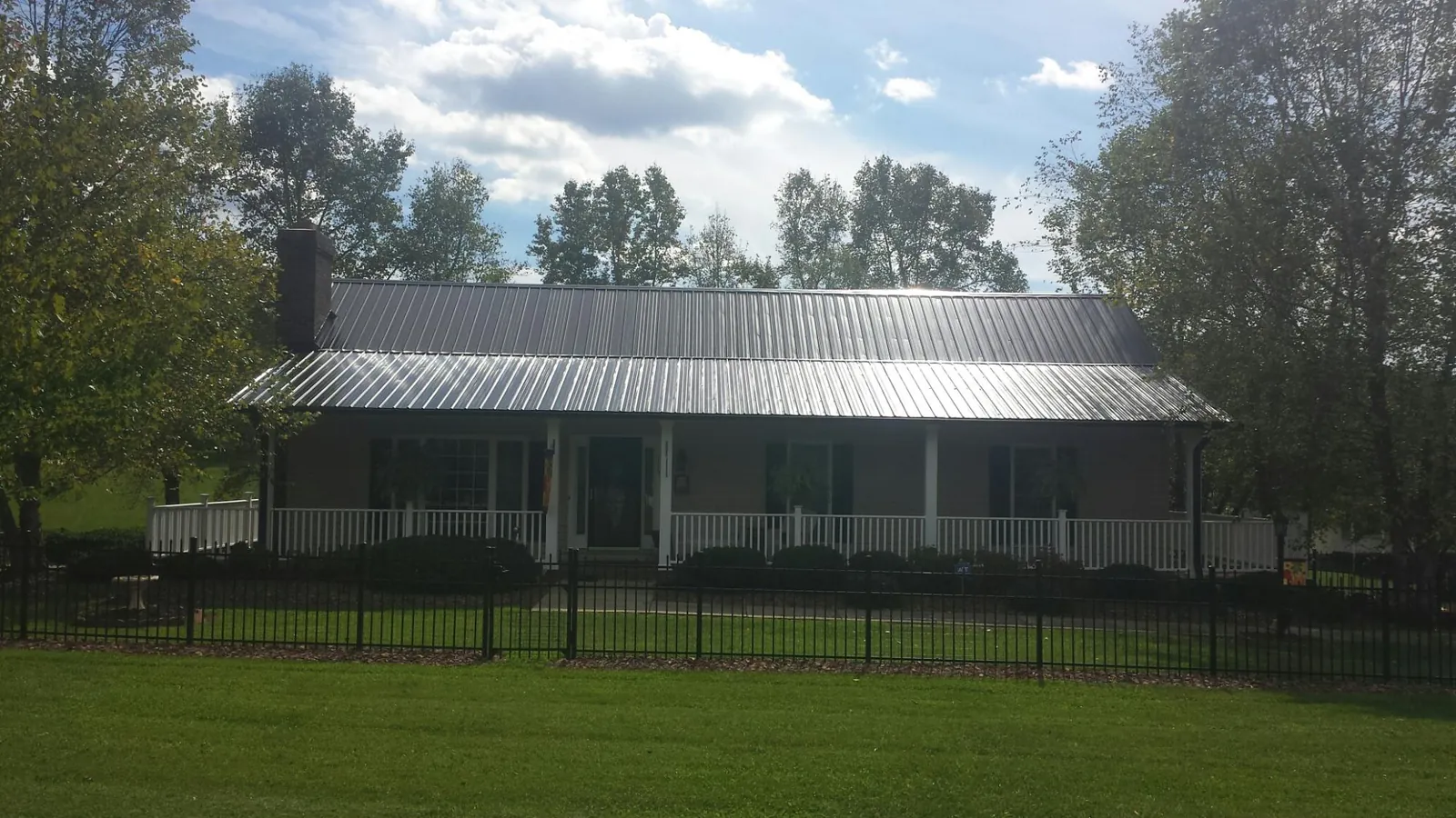 Gray metal roof on a brick ranch with a full width front porch — Gutter Guard Installation work by our crew in North Newton