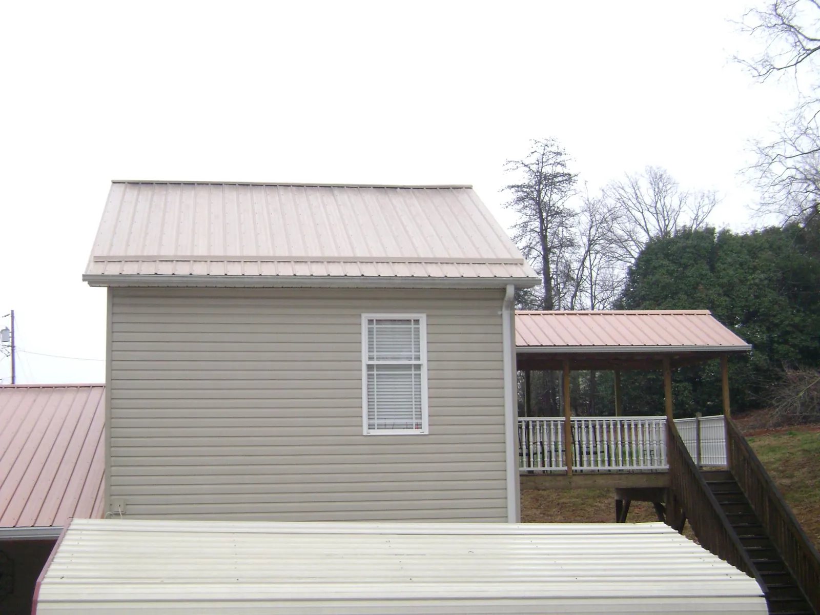 Tan metal roofs on a two story addition and attached porch, from a Roof Replacement job in North Newton