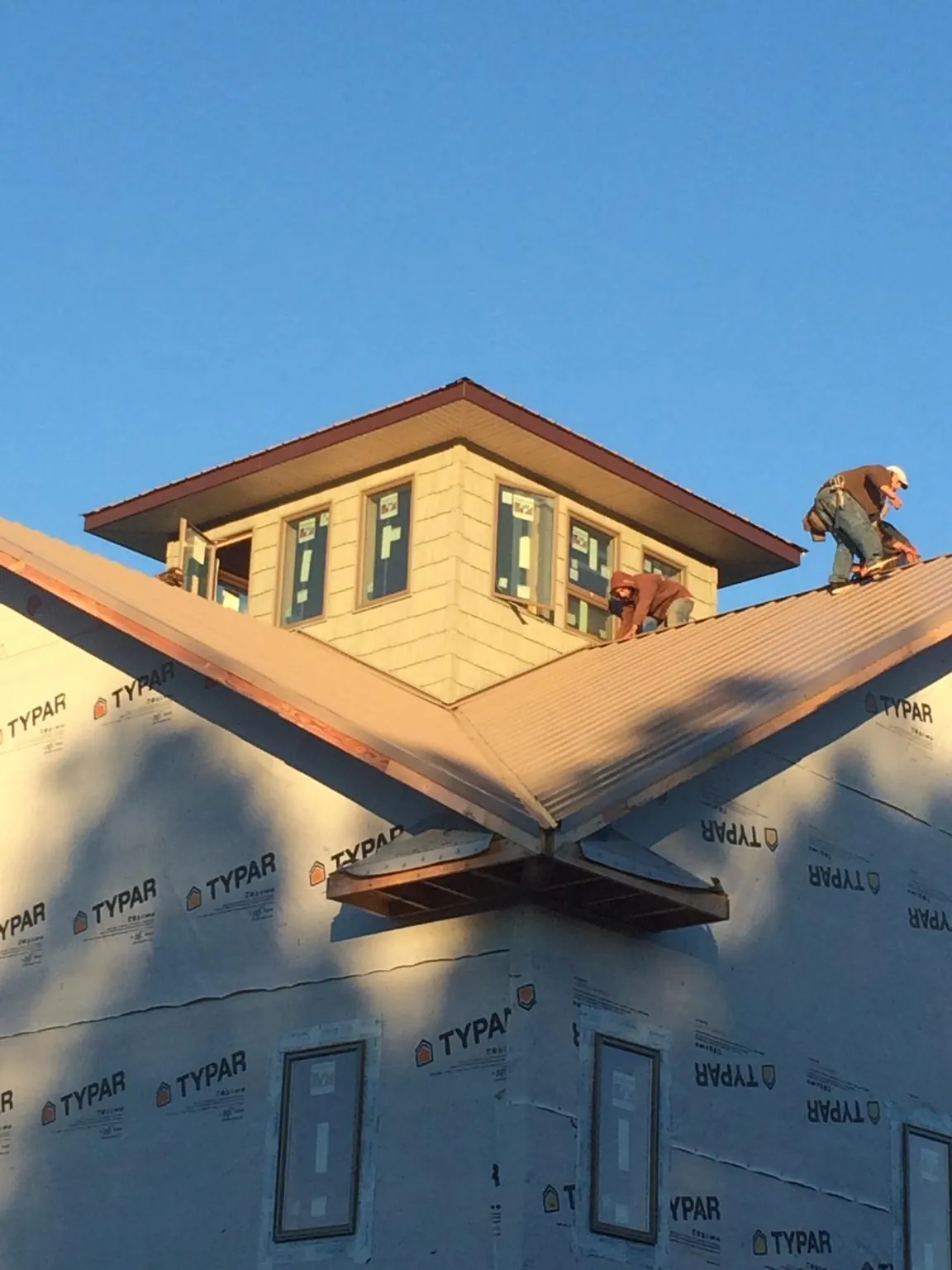 Roofers working around a rooftop cupola on a new metal roof at sunset — Roof Waterproofing in North Newton by Roofing Brothers